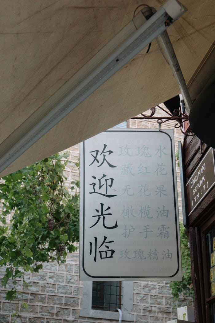 A traditional Chinese welcome sign hangs outside on a busy urban street.