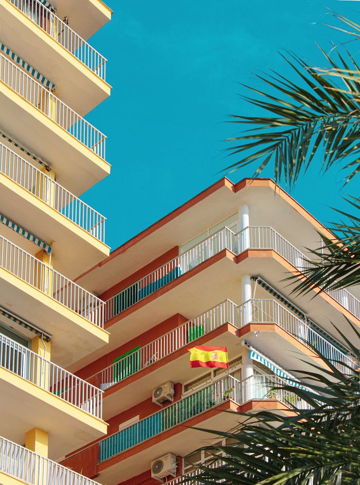 Bright modern apartment building in Spain with balconies and a Spanish flag.