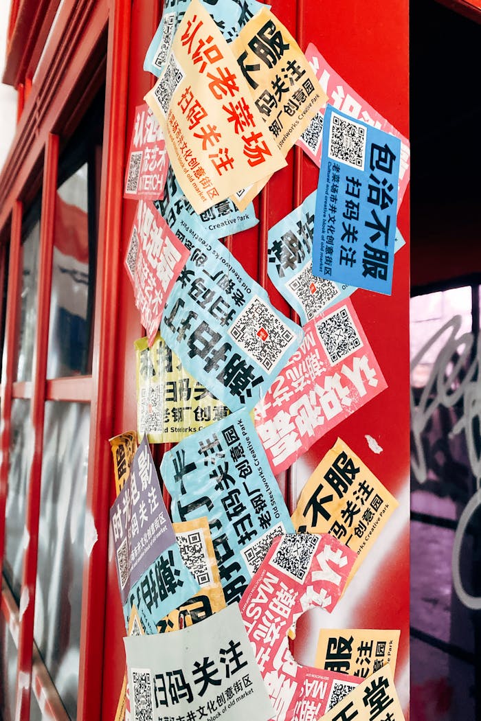 Vividly colored Chinese stickers on a red wall in Xian Shi, China, showcasing various advertisements.
